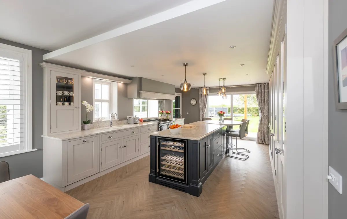 The same Burgh by Sands kitchen seen from the dining end, pale in-frame cabinets running the length of the room