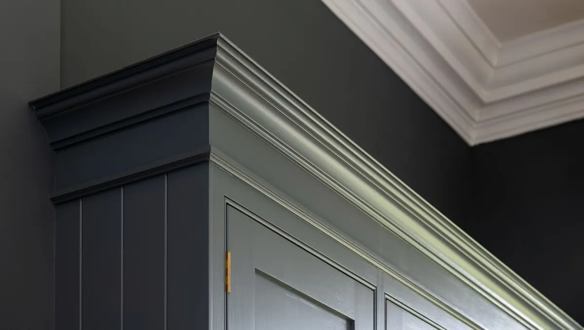Close detail of hand-painted in-frame cabinets, the cornice picked out against a darker painted wall