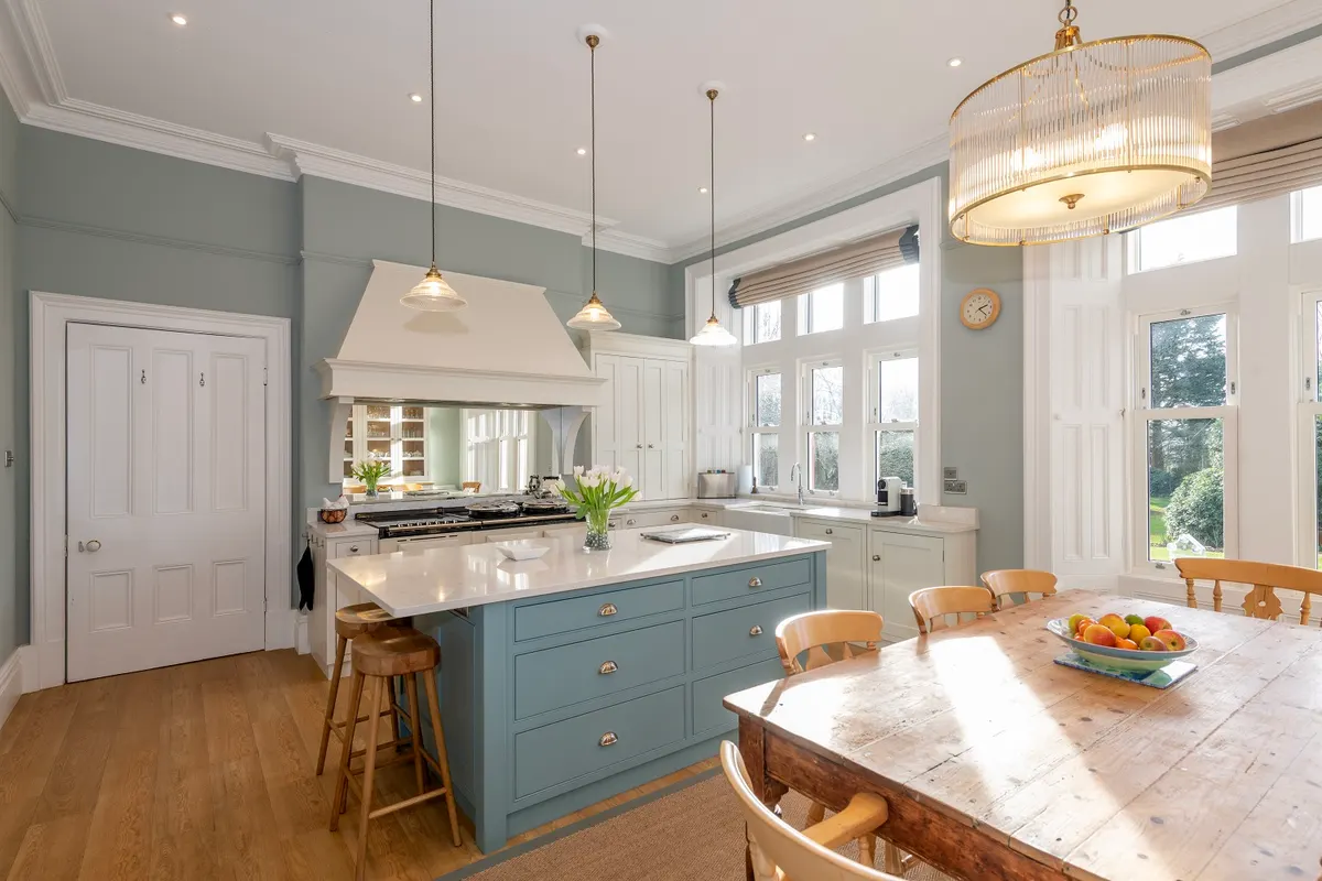 Kitchen at the Old Vicarage, Mealsgate, with a painted extractor canopy, sash windows and a scrubbed pine table